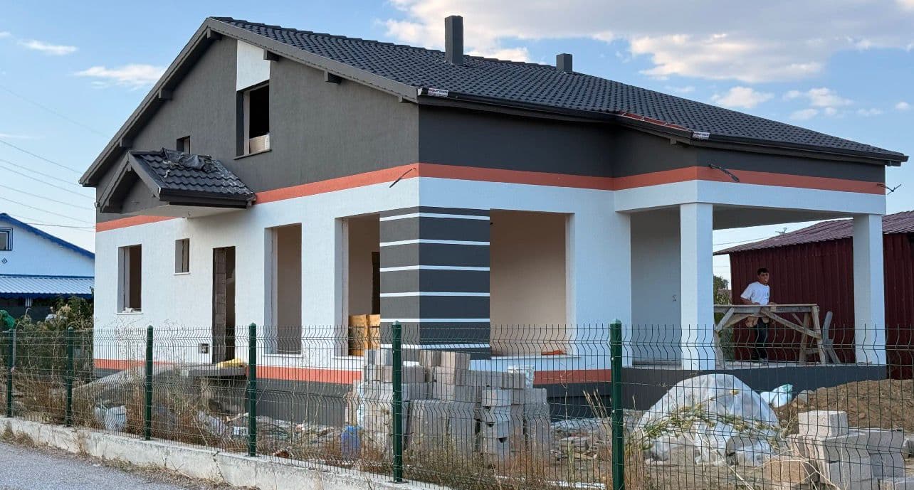 Aynı müstakil evin geniş açıdan dış cephe görünümü, iskele ve inşaat alanı